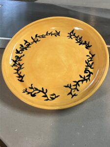 A golden yellow plate with hand painted black underglaze vines