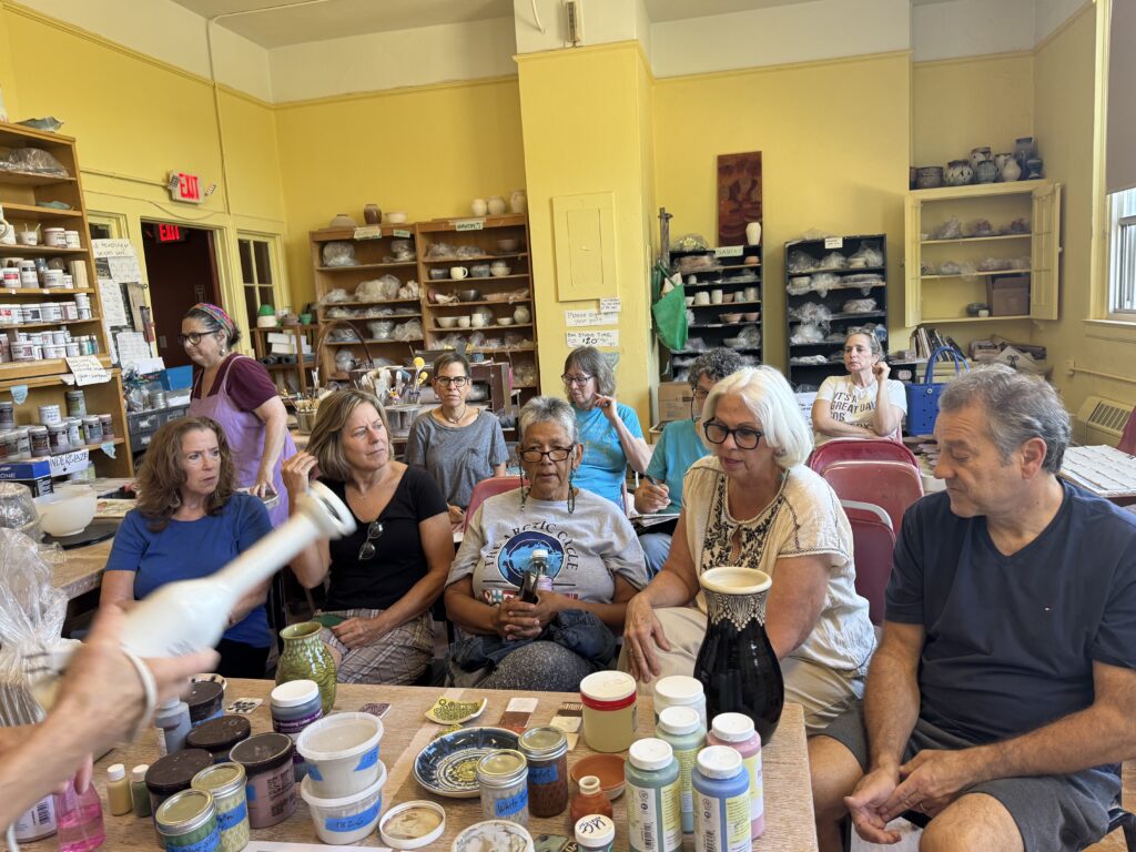 An image of warwick pottery students listening to Deboarah as she gives a slip demonstration